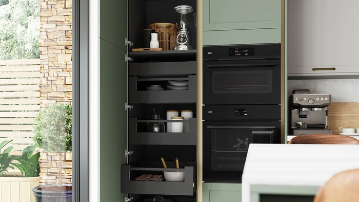 Space tower storage unit alongside integrated appliances in a Chester Reed Green Kitchen